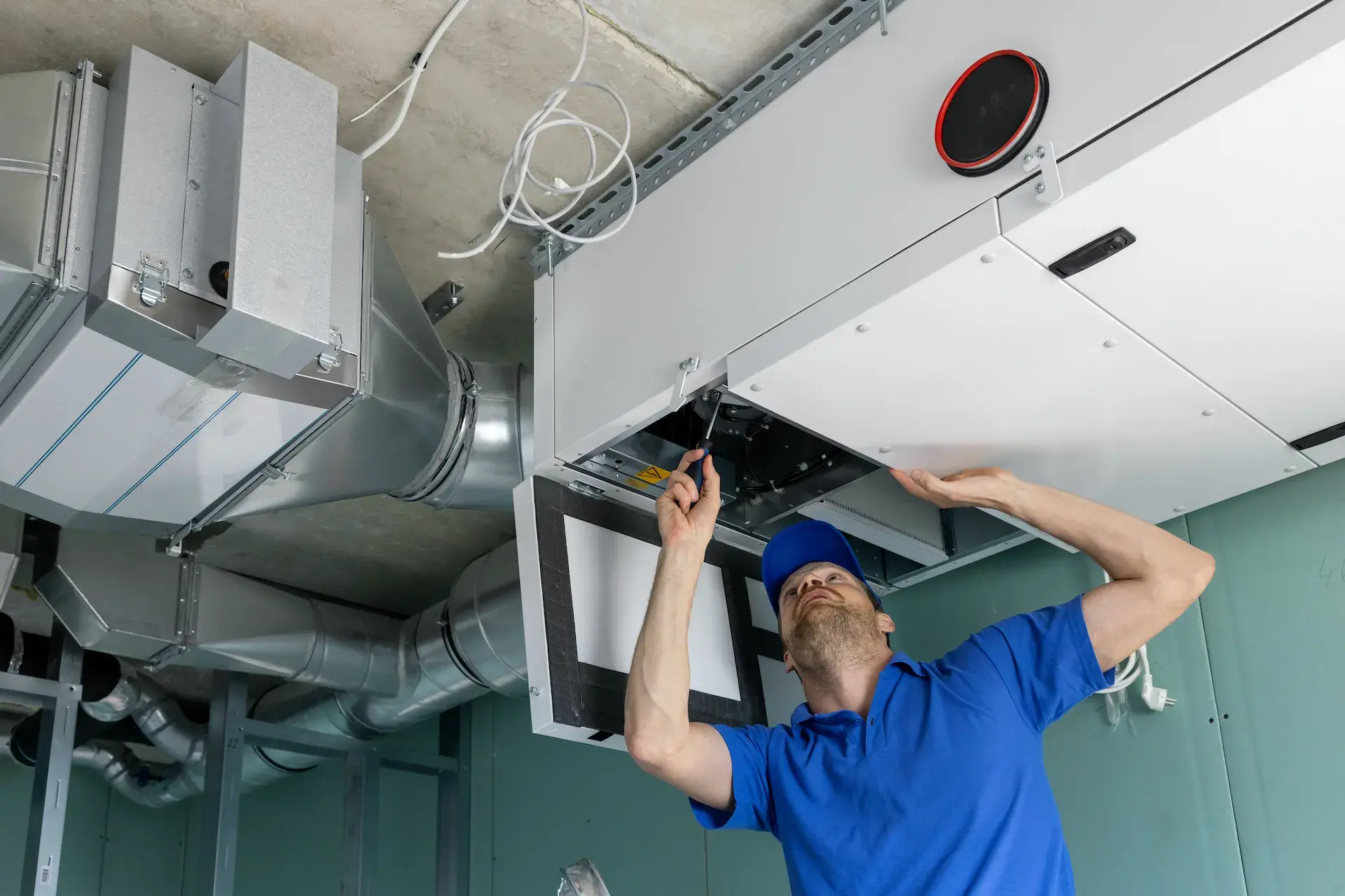 Technician installing commercial HVAC ductwork at the ceiling