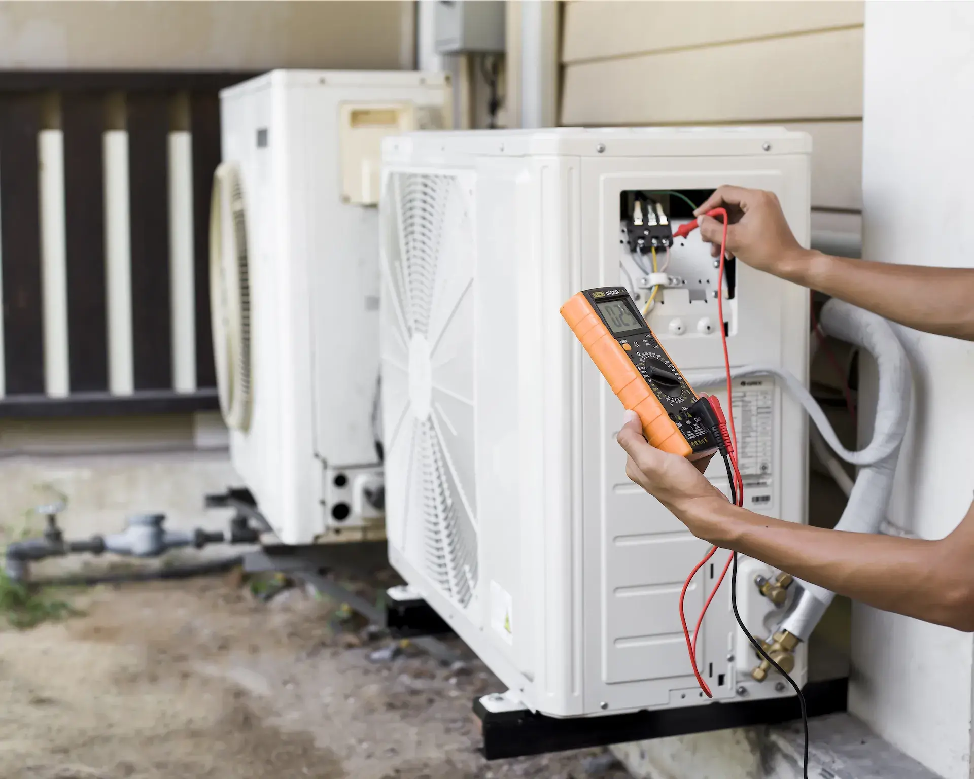 Technician testing a heat pump unit with a multimeter