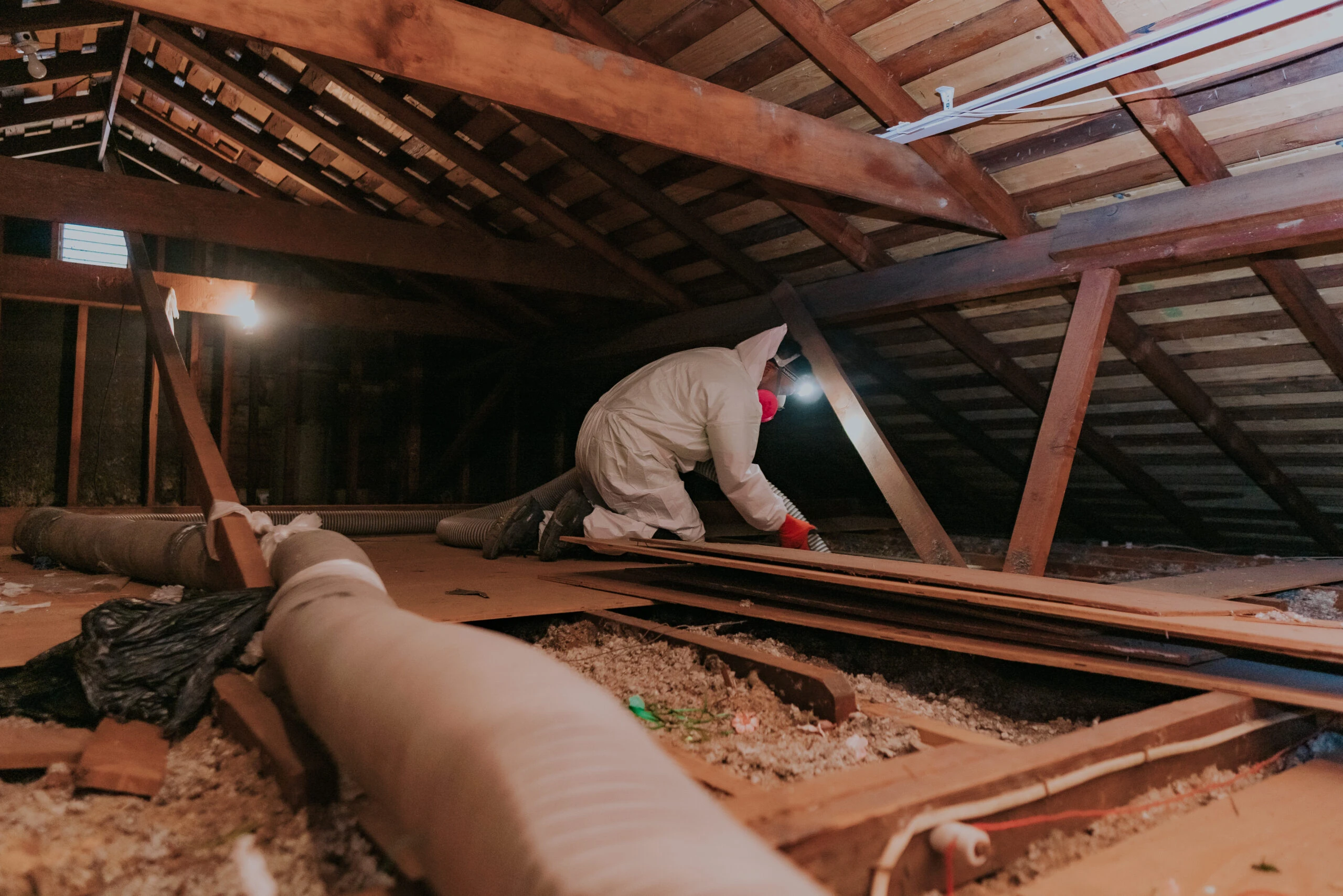 Technician in a protective suit cleaning an attic