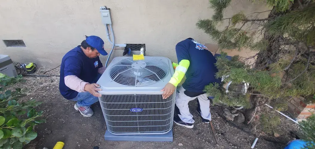 Two technicians positioning an air conditioner condenser